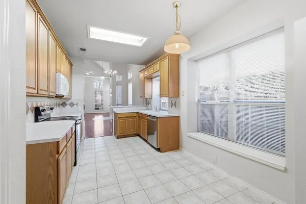 a large kitchen with kitchen island a large window a sink stainless steel appliances and cabinets
