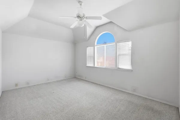 an empty room with chandelier fan and windows