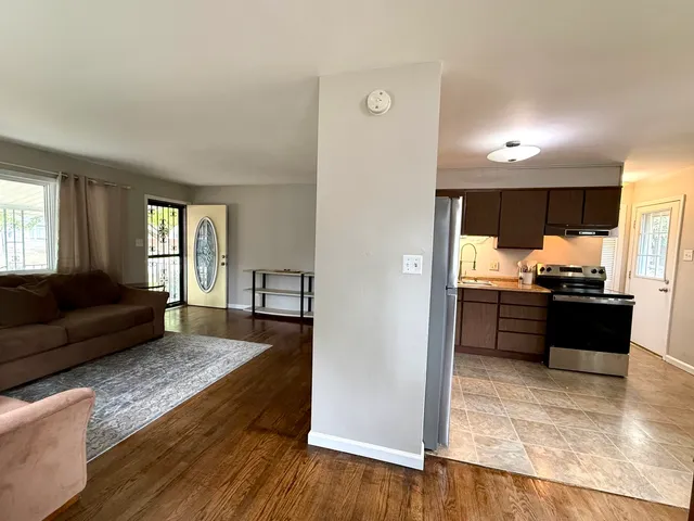 a living room with stainless steel appliances kitchen island granite countertop wooden floor a couch and a window