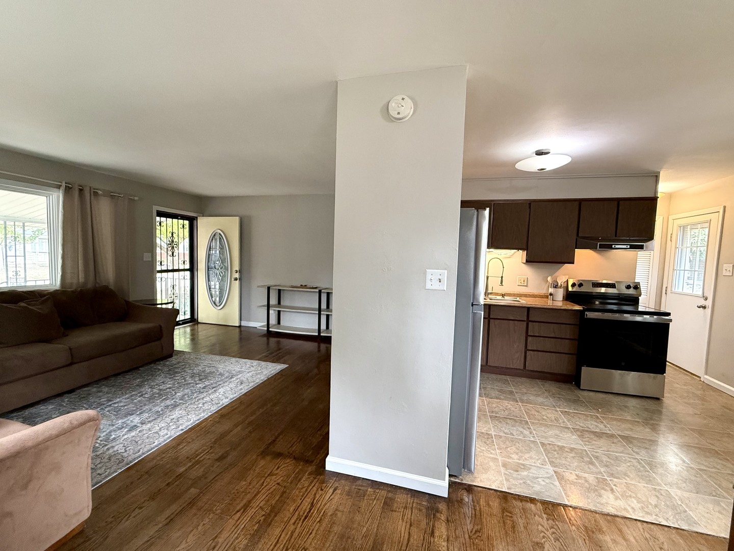509 Broadmeadow Road Rantoul, IL 61866 - Photo 7 of 18 a living room with stainless steel appliances kitchen island granite countertop wooden floor a couch and a window