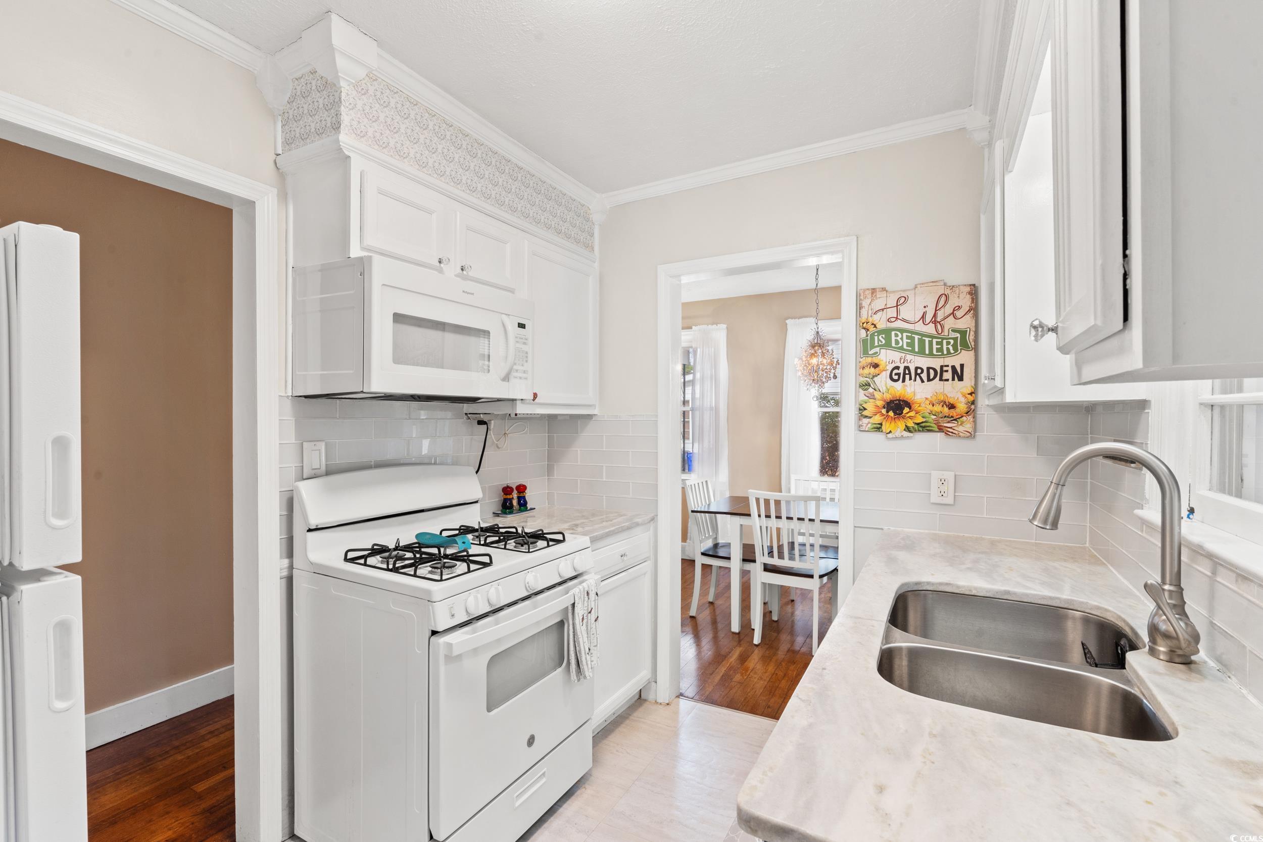 324 Edgewood Circle Conway, SC 29527 - Photo 12 of 31 Kitchen with white appliances, white cabinets, crown molding, light wood-style floors, and light stone countertops