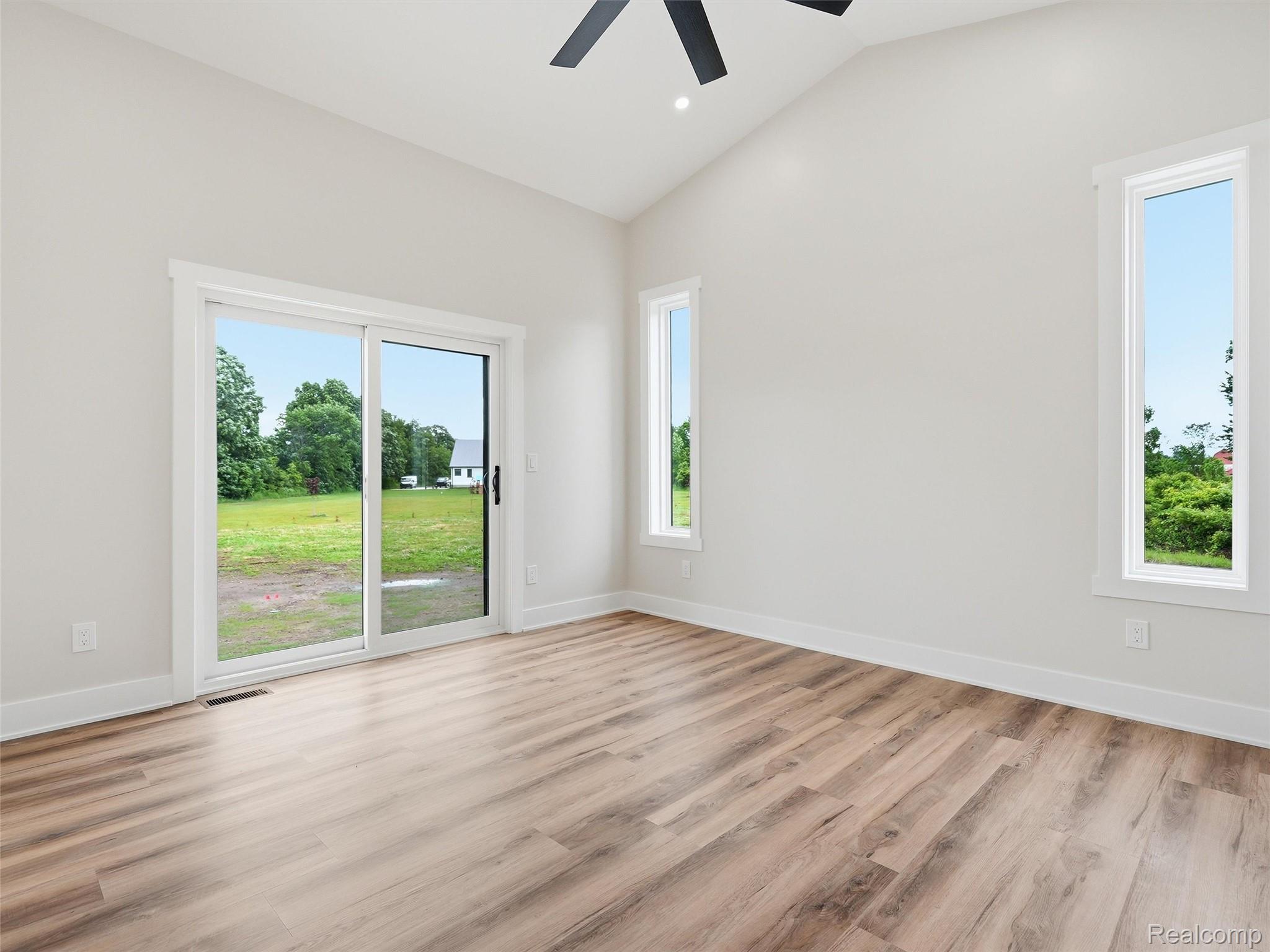 77850 Angling Road Richmond, MI 48062 - Photo 37 of 54 Vaulted ceiling room featuring wood-finish flooring, a sliding glass door, and two tall vertical windows