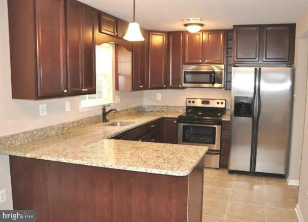 a kitchen with stainless steel appliances granite countertop a sink a stove and a refrigerator