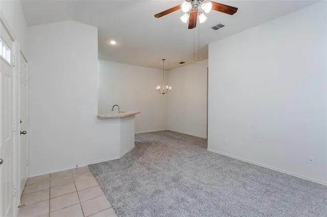 en empty room with an entryway and chandelier fan