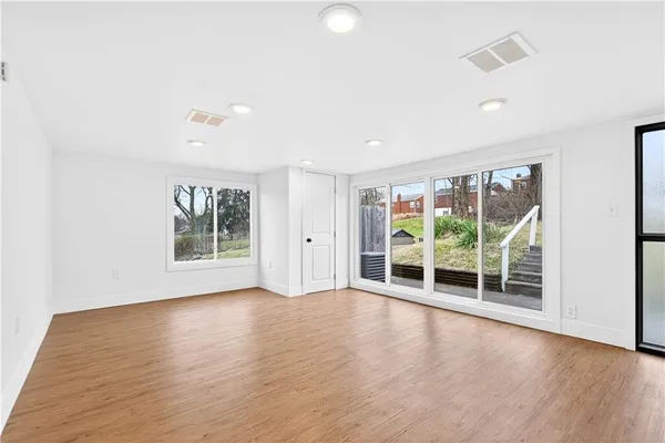 a view of an empty room with wooden floor and closet