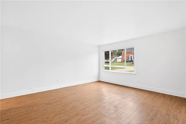 an empty room with wooden floor and window