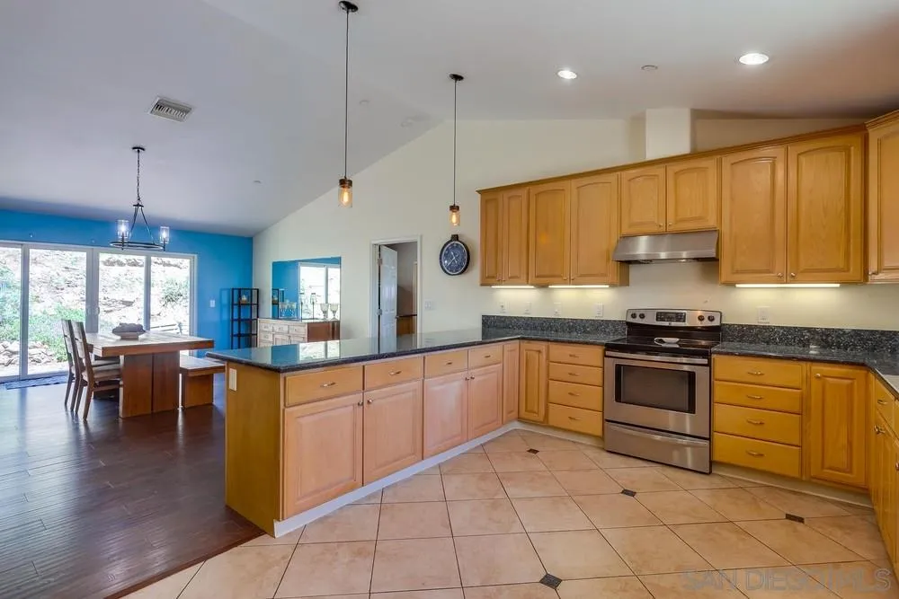 460 Pile Street Ramona, CA 92065 - Photo 11 of 25 a kitchen with stainless steel appliances granite countertop a stove top oven a sink dishwasher a dining table and chairs with wooden floor