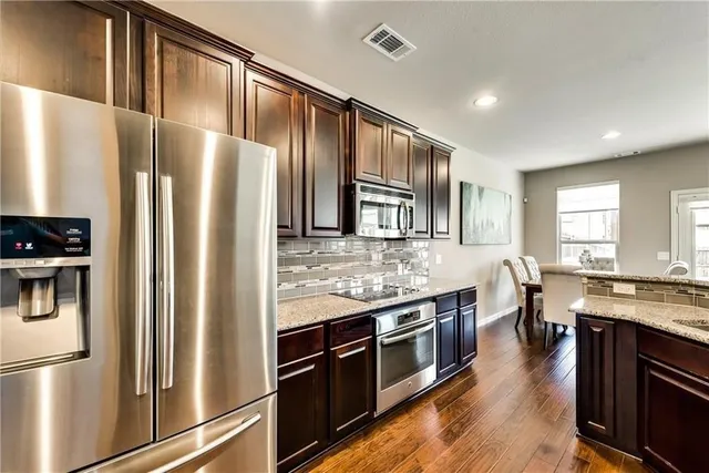 a kitchen with stainless steel appliances granite countertop a refrigerator a stove and a sink