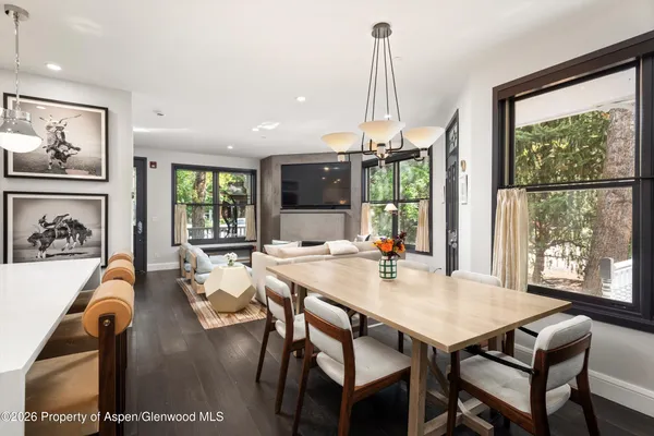 a view of a dining room and livingroom with furniture wooden floor a rug a painting and a chandelier