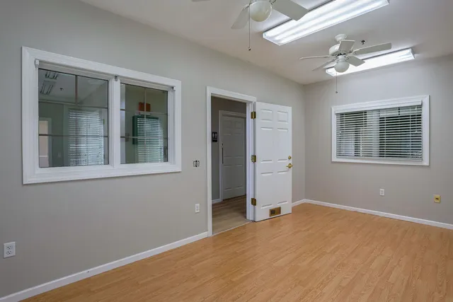 a view of empty room with wooden floor and fan