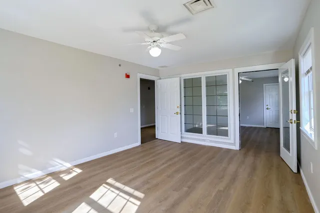 a view of an empty room with wooden floor and a window