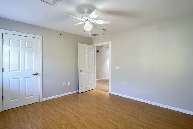 an empty room with wooden floor and fan