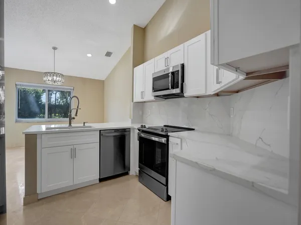 a kitchen with stainless steel appliances granite countertop white cabinets a microwave oven a sink and dishwasher