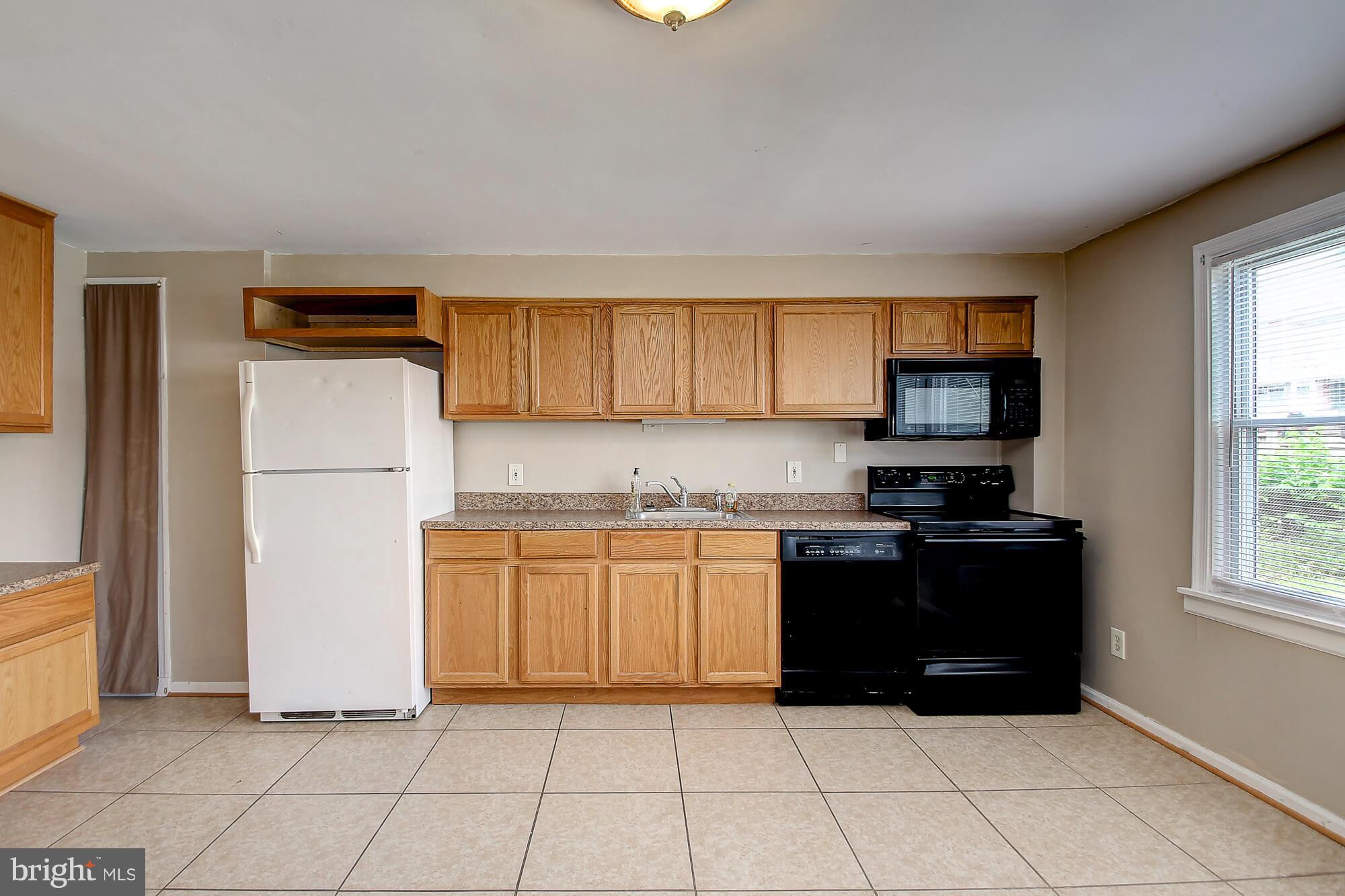 8036 Wynbrook Road Baltimore, MD 21224 - Photo 3 of 30 a kitchen with granite countertop a refrigerator and a stove top oven