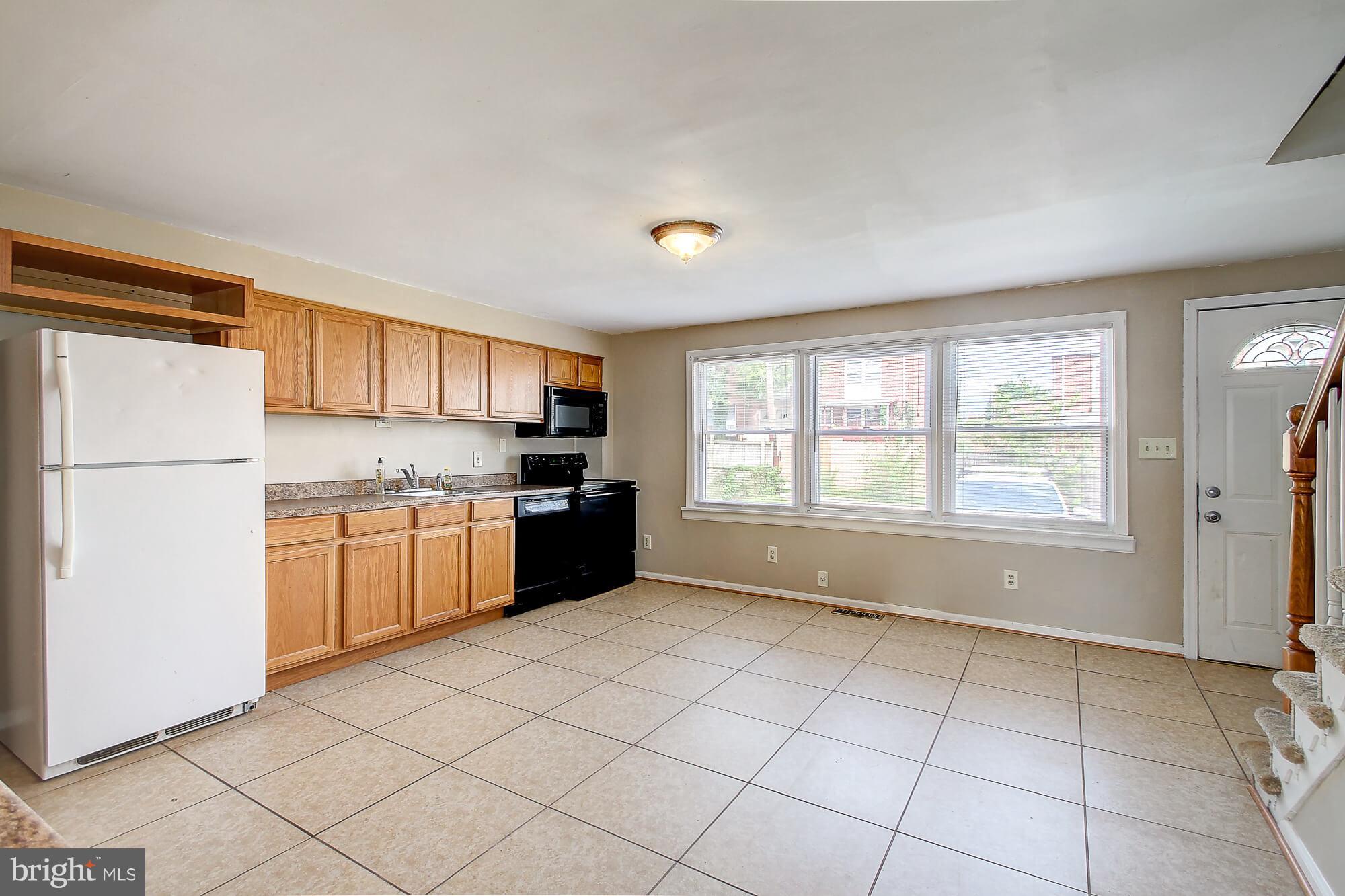 8036 Wynbrook Road Baltimore, MD 21224 - Photo 6 of 30 a kitchen with a refrigerator a stove top oven a sink and cabinets