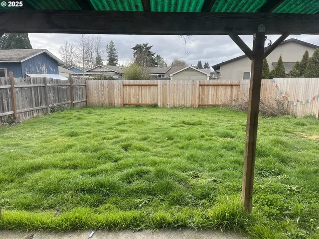 a view of a backyard with barn and wooden fence
