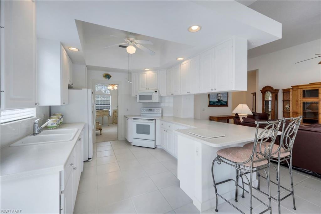 3059 Ellice Way Naples, FL 34119 - Photo 13 of 50 a kitchen with stainless steel appliances a table chairs refrigerator and sink