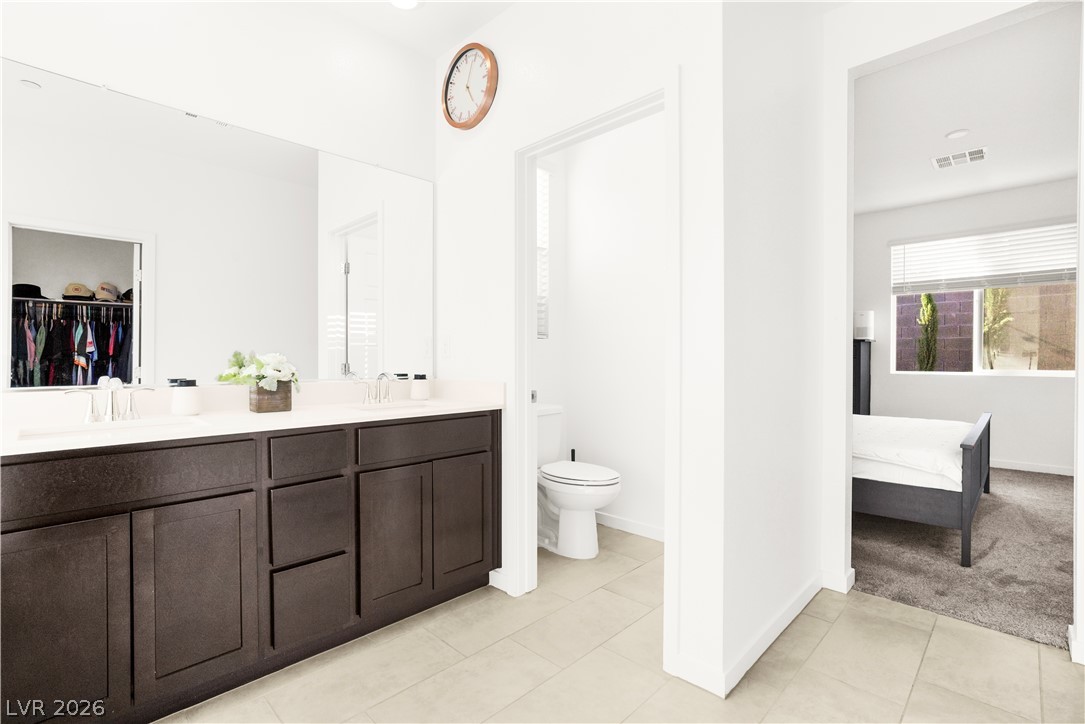 9398 Noble Fir Rdg Court Las Vegas, NV 89143 - Photo 15 of 36 A dual-sink vanity with abundant storage anchors this pristine primary bathroom.