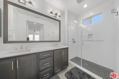 a bathroom with a double vanity sink mirror and shower
