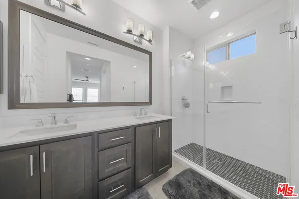 a bathroom with a double vanity sink mirror and shower