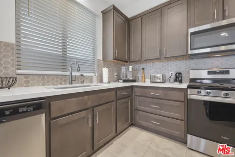 a kitchen with stainless steel appliances granite countertop a sink and cabinets with wooden floor