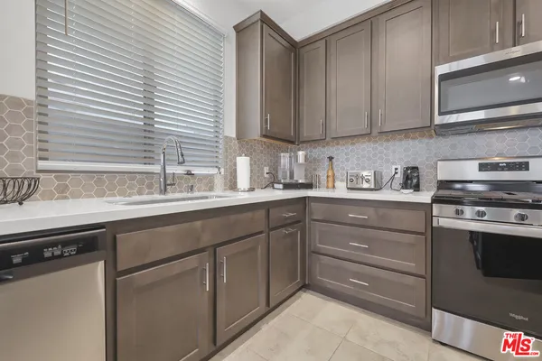 a kitchen with stainless steel appliances granite countertop a sink and cabinets with wooden floor