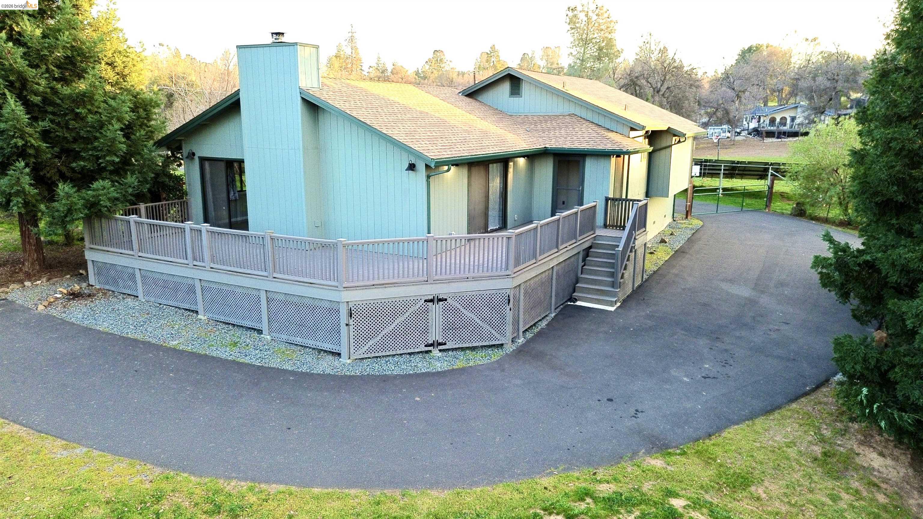 13033 Clements Road Groveland, CA 95321 - Photo 2 of 23 View of front facade with a wooden deck, wraparound driveway, roof with shingles, and a chimney
