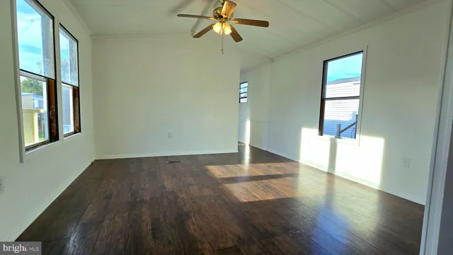 a view of empty room with wooden floor and fan