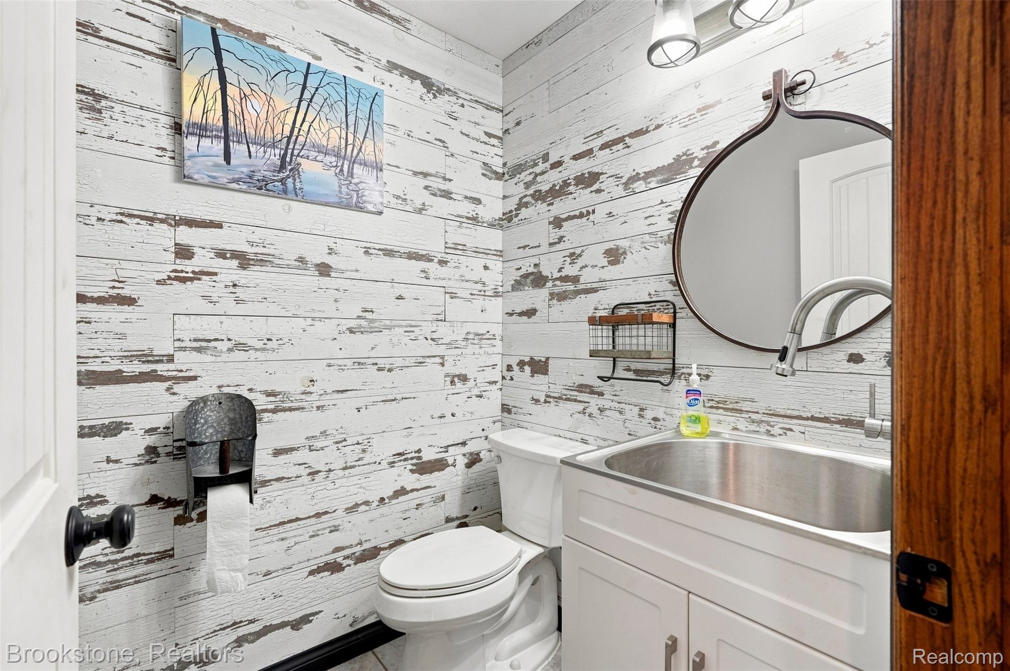 1775 Dutcher Road Howell, MI 48843 - Photo 14 of 41 Distressed wood-finish accent wall, white vanity with stainless steel sink, contemporary mirror, and industrial-style lighting