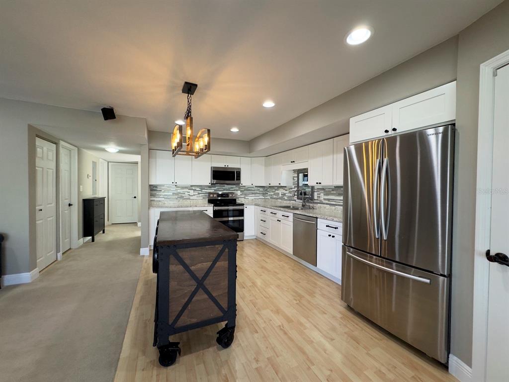 559 Fairways Circle Ocala, FL 34472 - Photo 9 of 29 a kitchen with refrigerator a microwave a stove and white cabinets with wooden floor