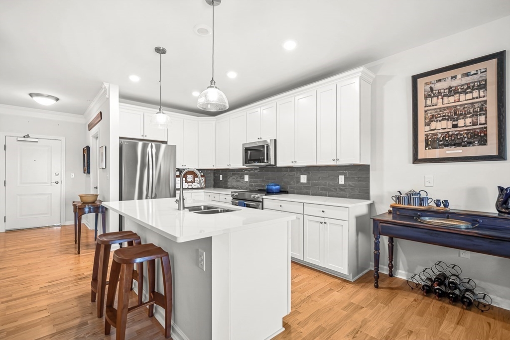 2 Stratton Drive, Unit 307 Woburn, MA 01801 - Photo 7 of 21 a kitchen with a refrigerator a stove a sink dishwasher a dining table and chairs with wooden floor