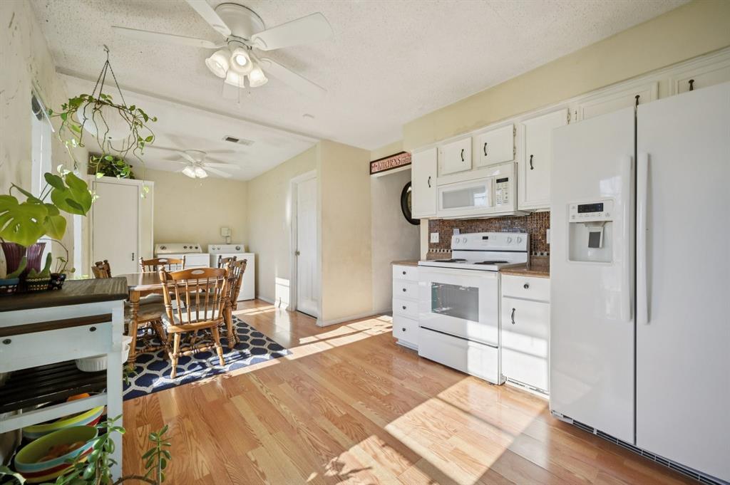 1021 Pleasant Valley Road Garland, TX 75040 - Photo 13 of 32 a kitchen with stainless steel appliances a stove top oven a refrigerator a dining table and chairs with wooden floor