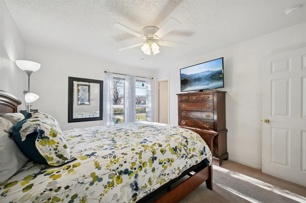 1021 Pleasant Valley Road Garland, TX 75040 - Photo 17 of 32 a bedroom with a bed and a chandelier