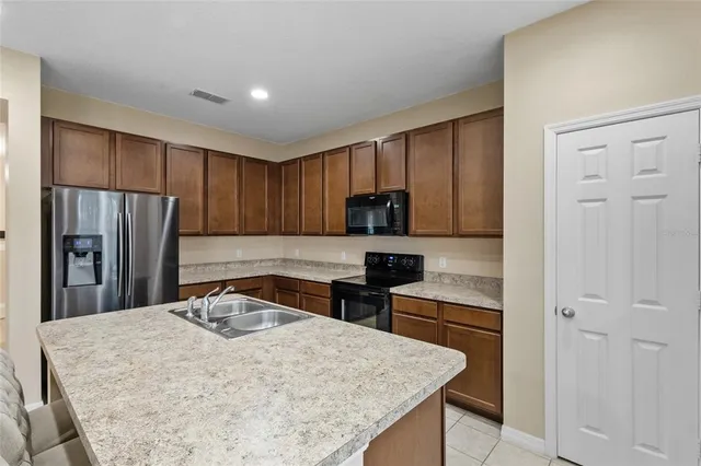 a kitchen with a refrigerator a stove top oven a sink and cabinets