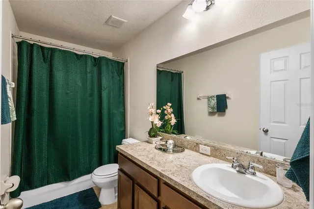 a bathroom with a granite countertop sink toilet and mirror