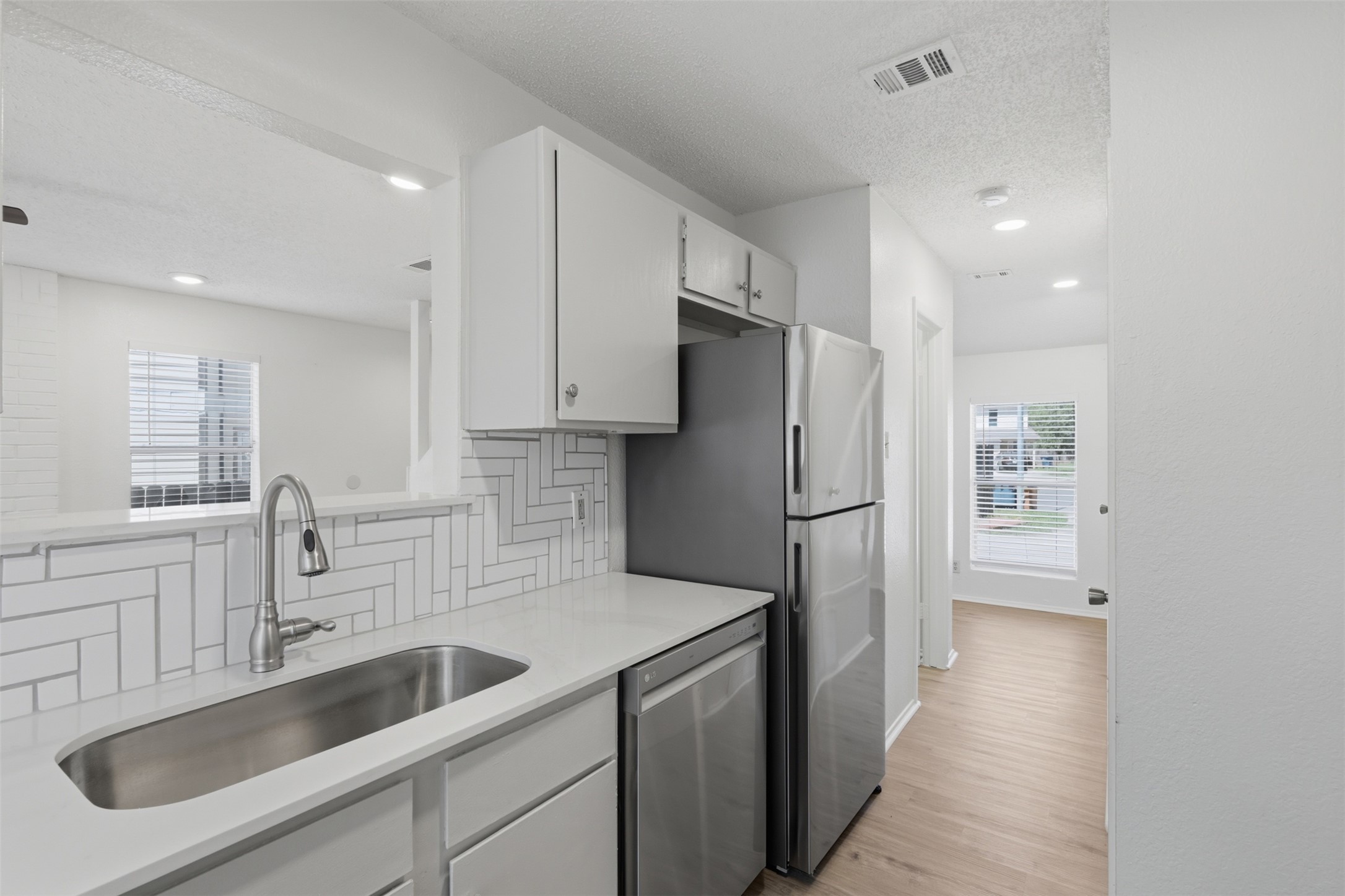 6105 Conti Court, Unit A Austin, TX 78744 - Photo 13 of 36 a kitchen with a sink a refrigerator and cabinets