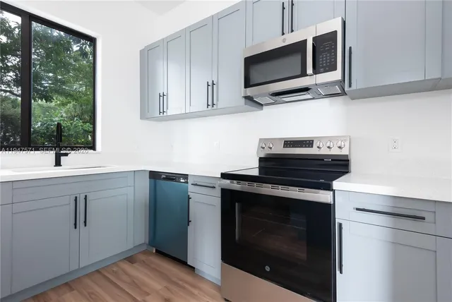 a kitchen with cabinets stainless steel appliances a sink and a microwave