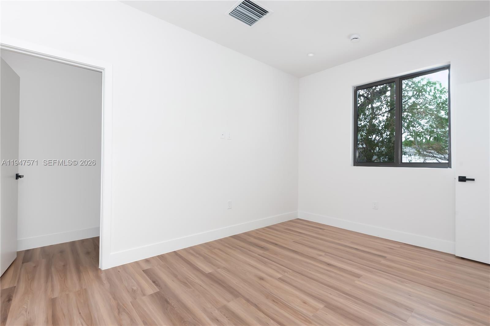 4517 Northwest 3rd Street Miami, FL 33126 - Photo 22 of 34 an empty room with wooden floor and windows