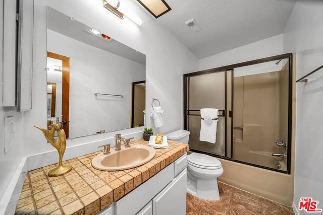 a bathroom with a granite countertop sink toilet a mirror and shower