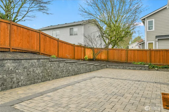 a view of backyard with large tree and wooden fence