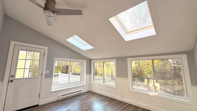 a view of an empty room with a window and wooden floor