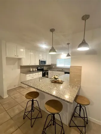 a kitchen with stainless steel appliances granite countertop a stove a sink a refrigerator white cabinets with chairs and couches