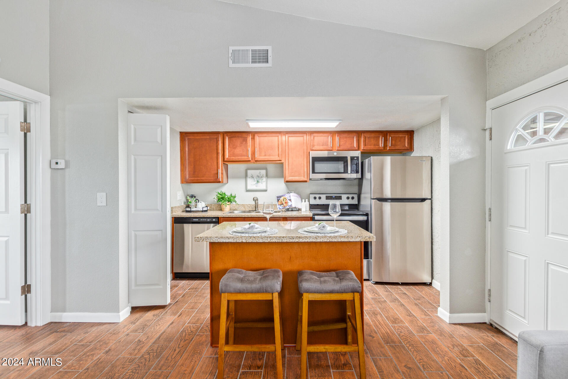 1602 East Ocotillo Road, Unit 121 Phoenix, AZ 85016 - Photo 12 of 31 a kitchen with a refrigerator a stove and a dining table with wooden floor