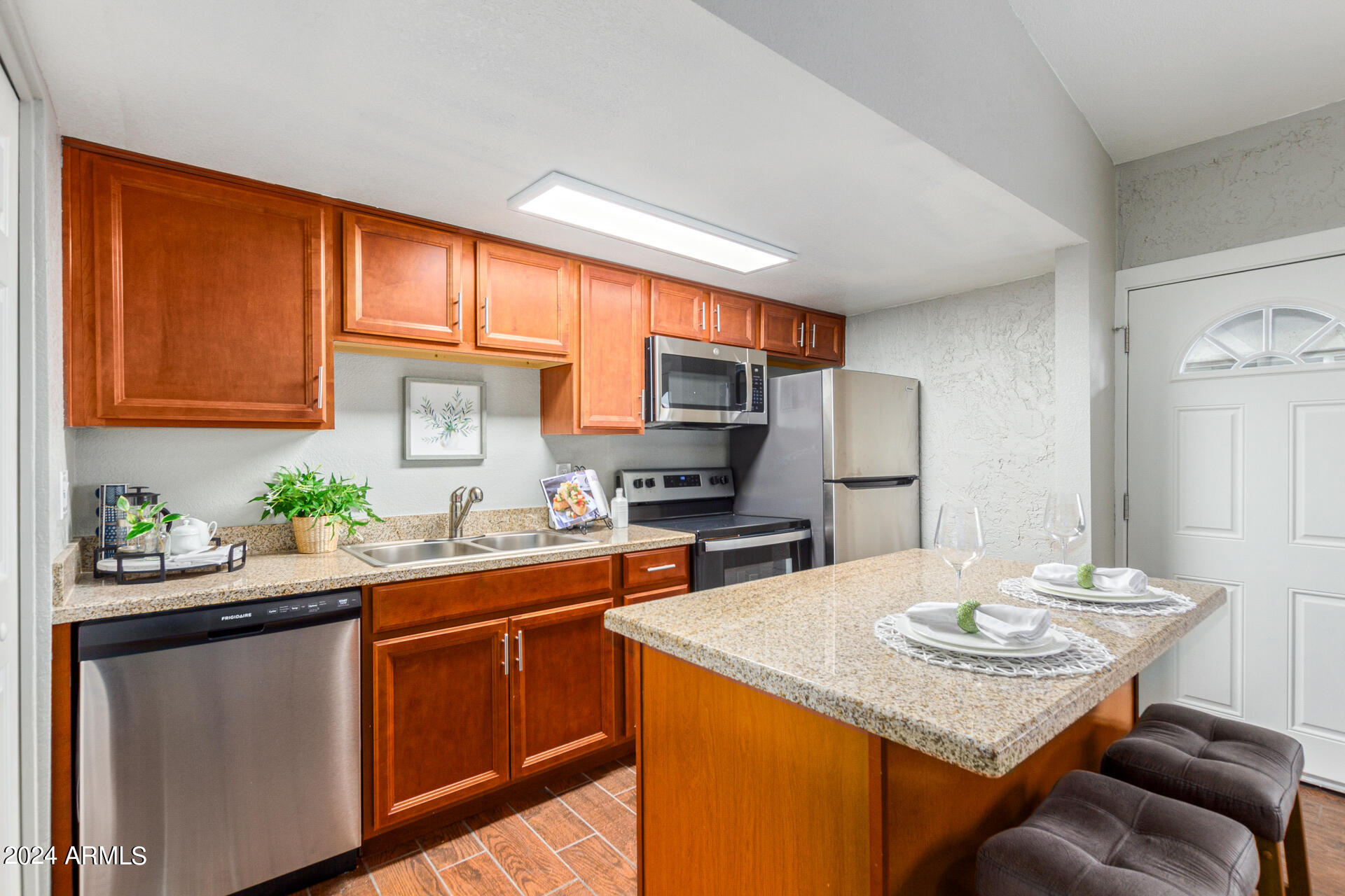 1602 East Ocotillo Road, Unit 121 Phoenix, AZ 85016 - Photo 9 of 31 a kitchen with stainless steel appliances granite countertop a sink dishwasher stove refrigerator and microwave with wooden floor