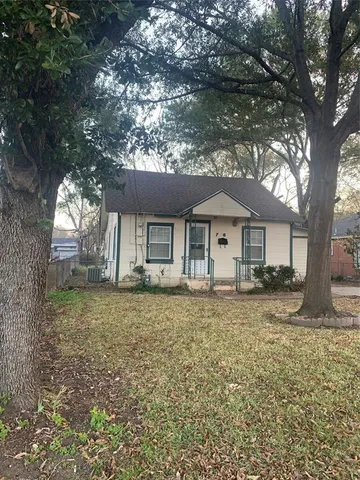 a front view of a house with a garden and trees