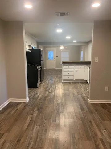 an empty room with wooden floor cabinet and windows