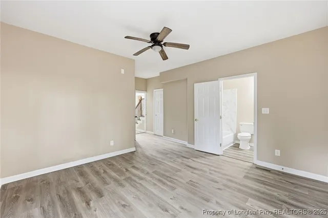a view of empty room with wooden floor and ceiling fan