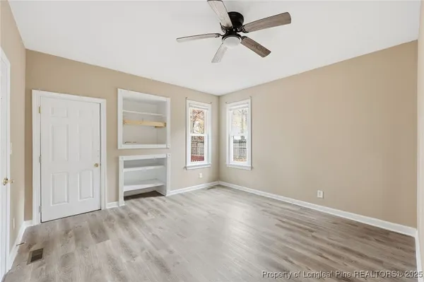 a view of empty room with wooden floor and fan