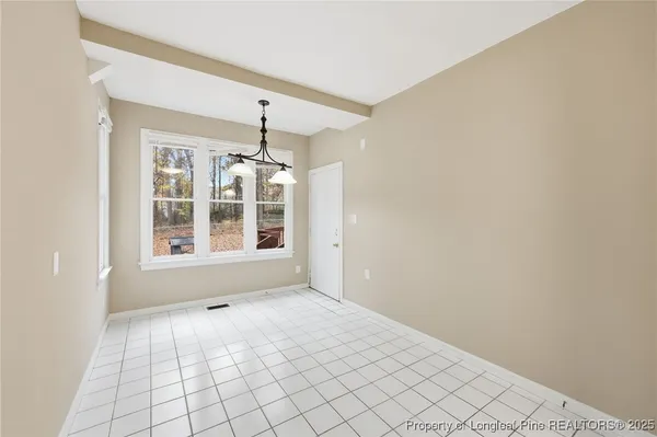 a view of an empty room with chandelier fan