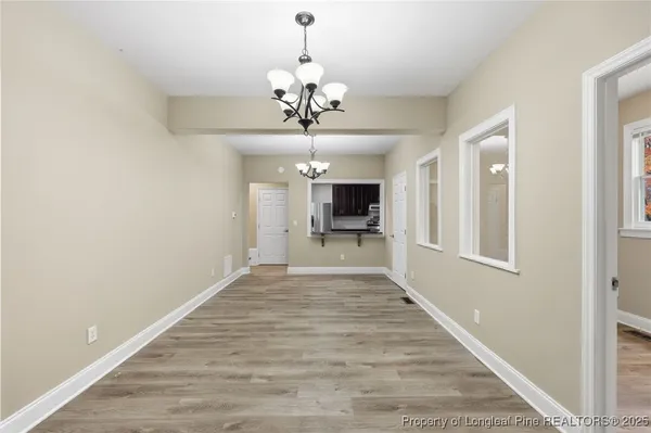 a view of a hallway with wooden floor and a chandelier